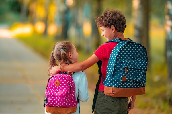 Imaging of children walking to school with backpacks and arms around each other