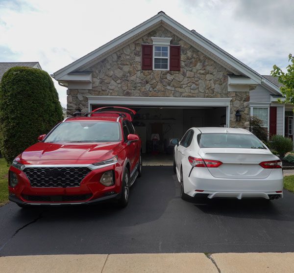 House with 2 cars in the driveway and the garage door open