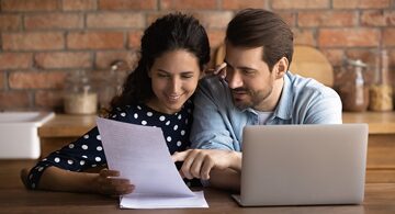 2 people looking at a website and paperwork